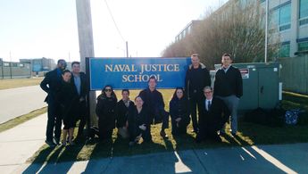 Mark Lund (standing right of sign) pictured at the Naval Justice School in Newport, RI with actors from the mock trial p