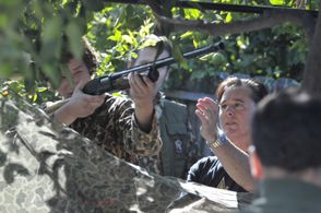 Paul (Josiah Lipscomb) raises a shotgun while Director, Stephen Mouton explains practical slide-barrel reloading and sho