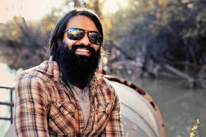 Outdoors. Rugged, bearded, hipster, long hair. Ethnically ambiguous. Fluent in Portuguese and Spanish.