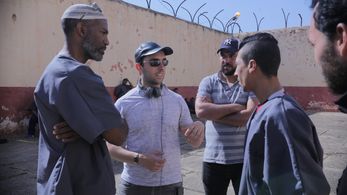 Director Aziz Tazi with Actor Ricco Ross and extras on set in a Moroccan prison.